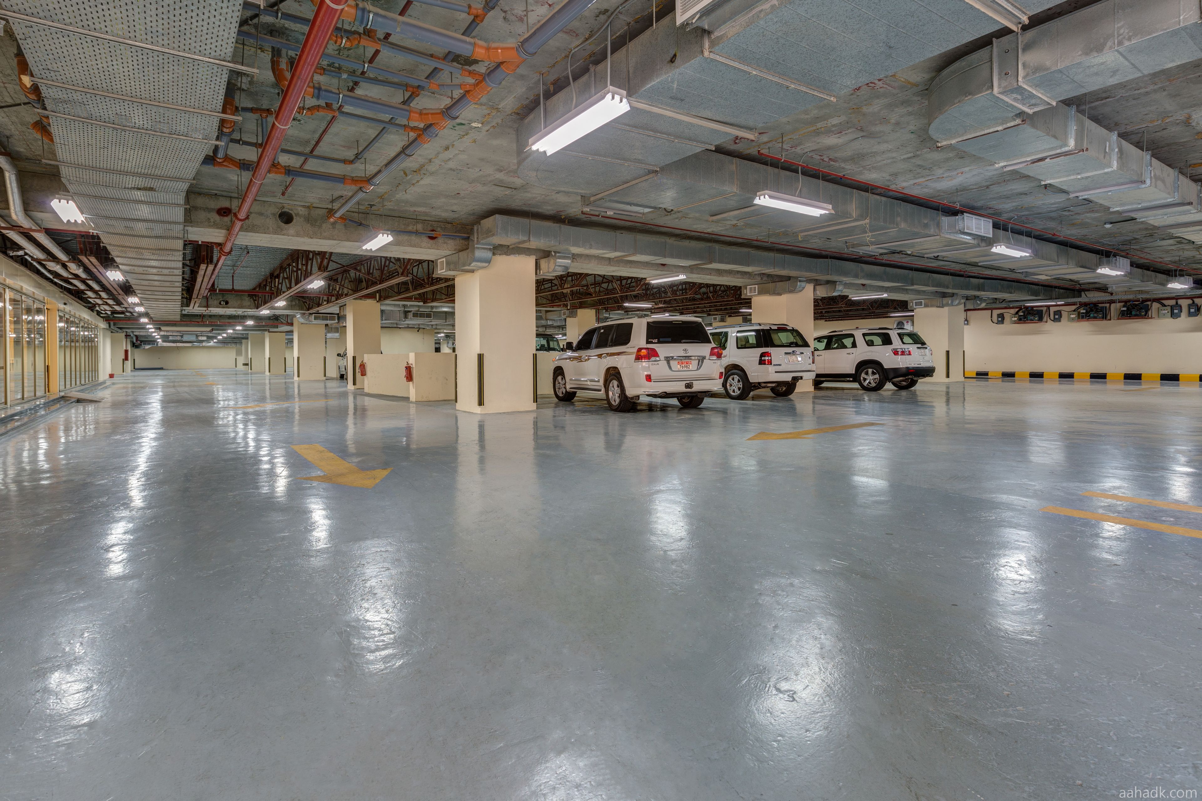 A spacious parking garage with multiple white SUVs parked.