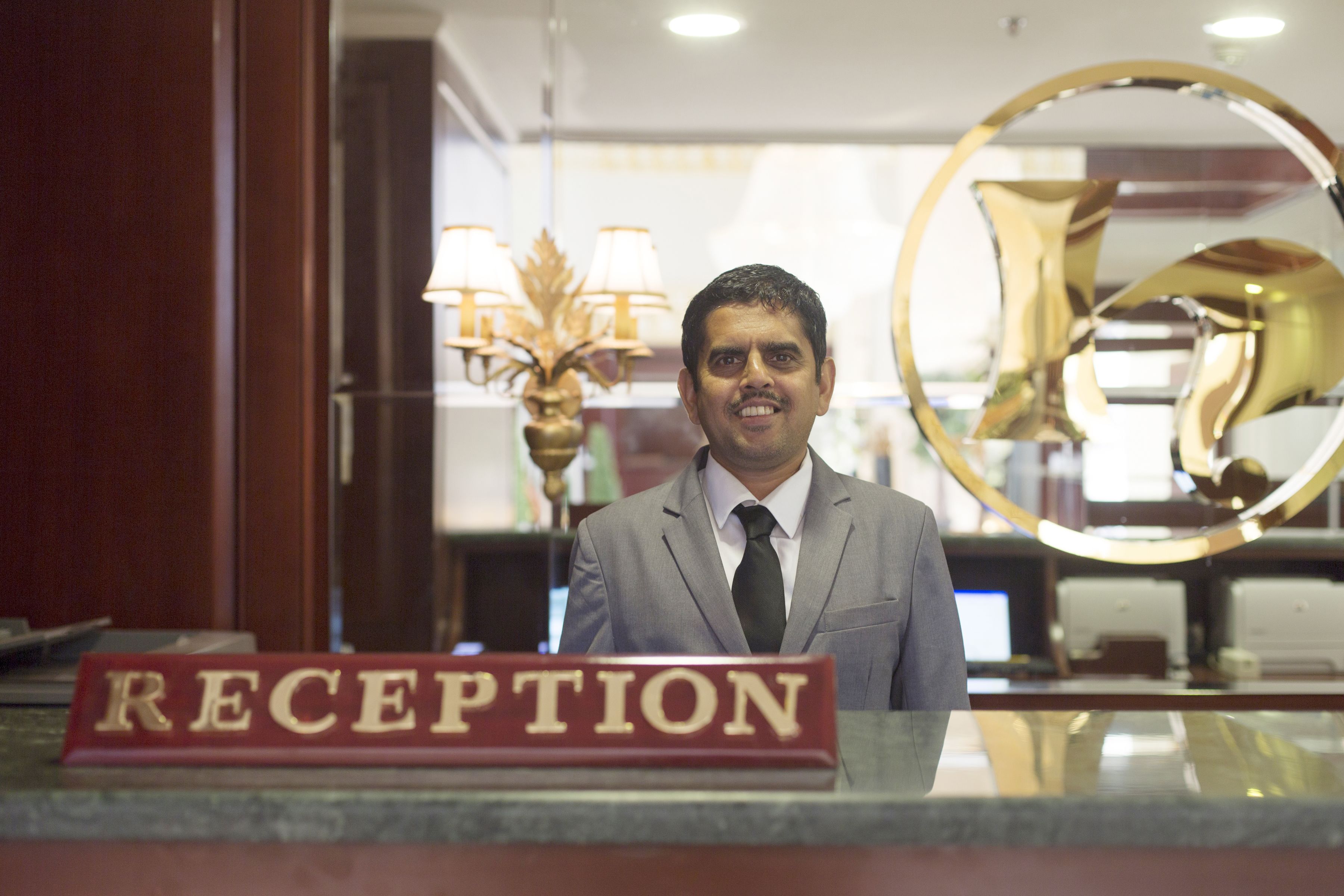 Un'area reception con un cartello 'RECEPTION', un lampadario e un grande specchio.