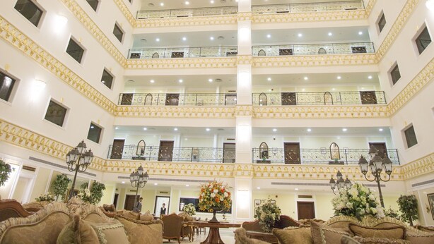 A multi-level hotel lobby with a central atrium, multiple floors, and a grand chandelier.