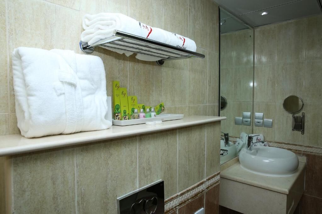 A bathroom with a sink, mirror, towel rack, and toiletries.
