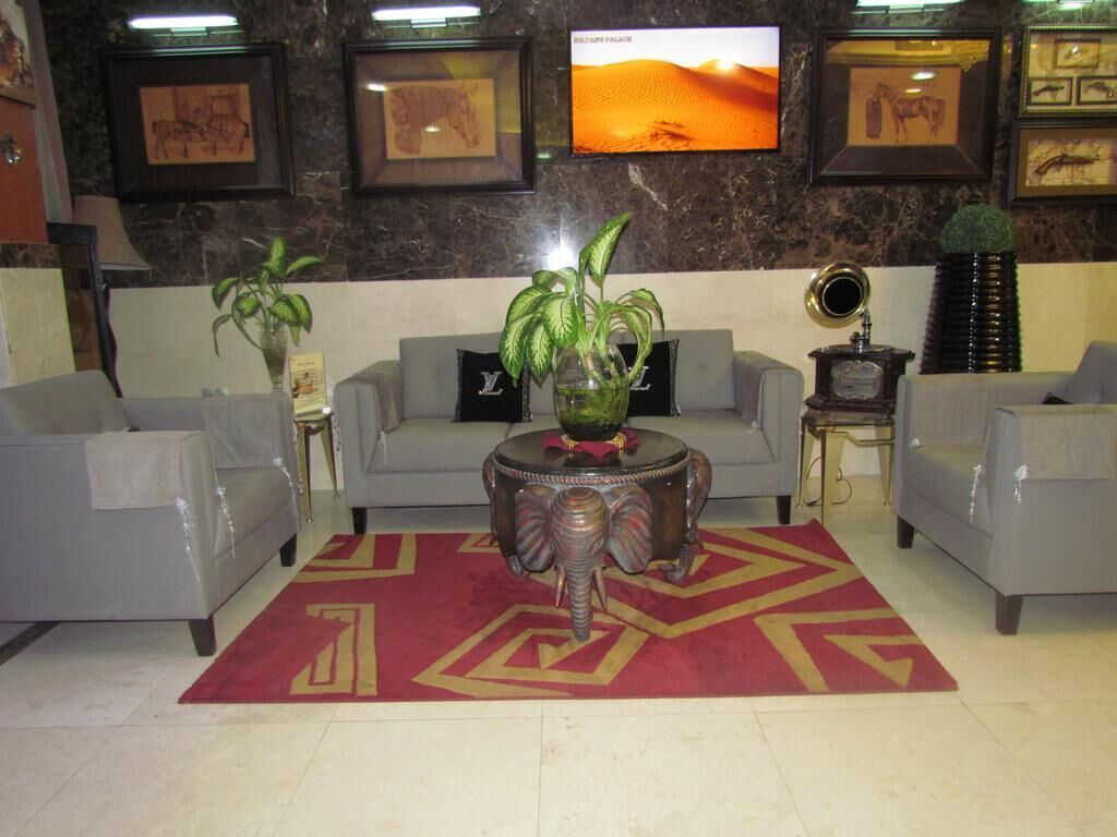 A lobby with a sofa set, a patterned rug, and framed artwork on the walls.