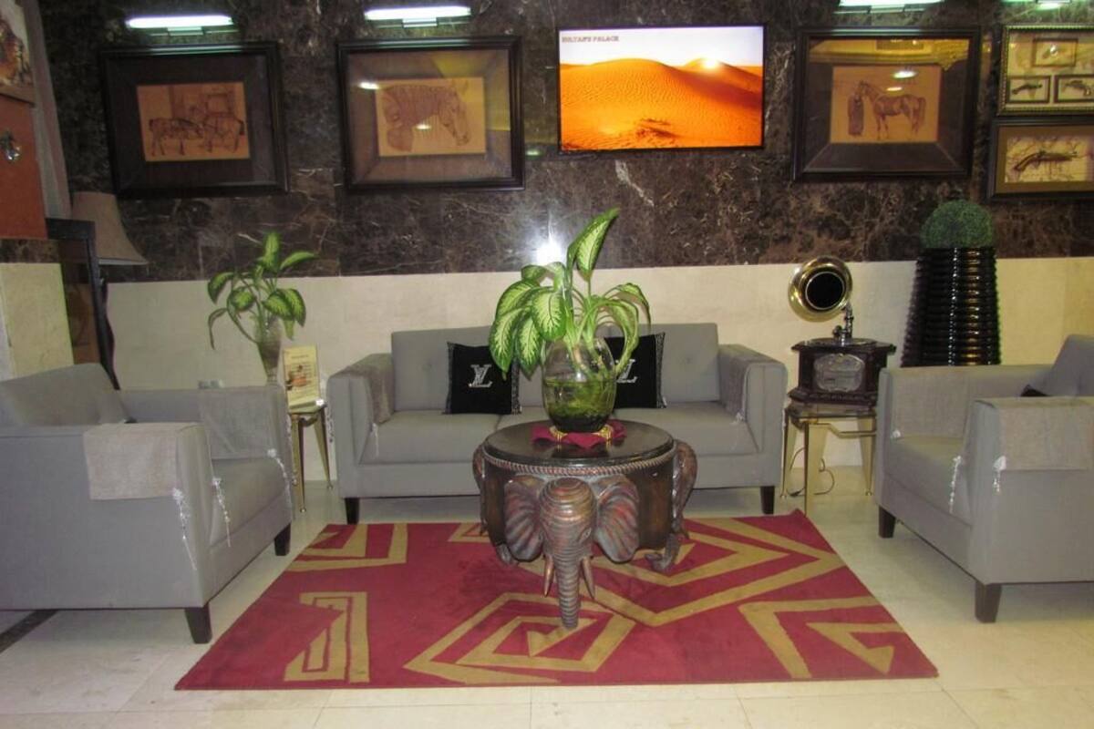 A lobby with a sofa set, a patterned rug, and framed artwork on the walls.