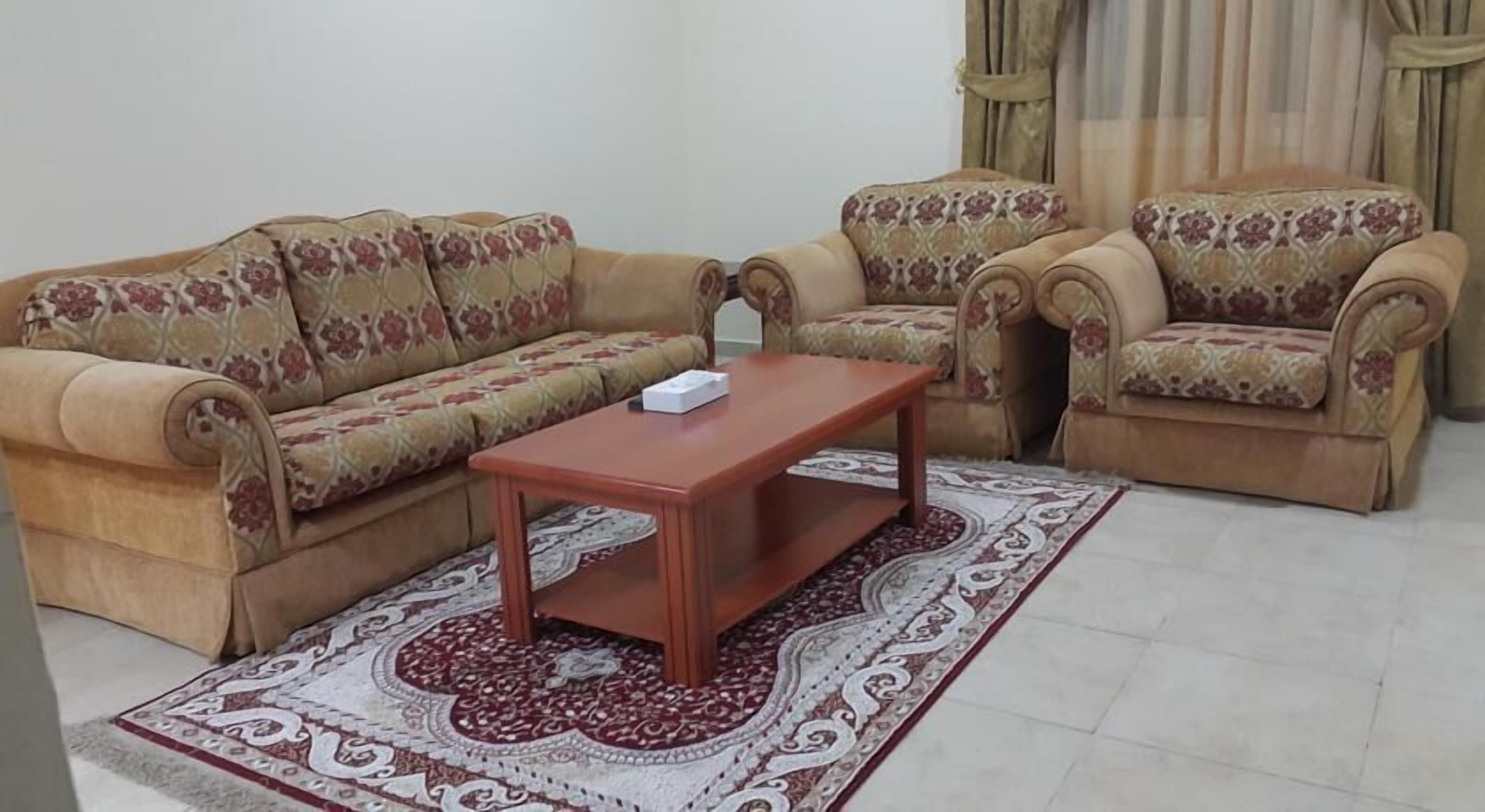 A living room with two sofas and a coffee table, a patterned rug, and curtains.