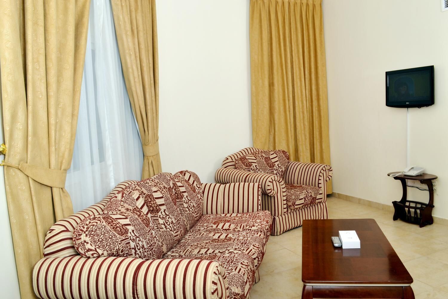 A living room with a sofa set, a coffee table, and a TV mounted on the wall.