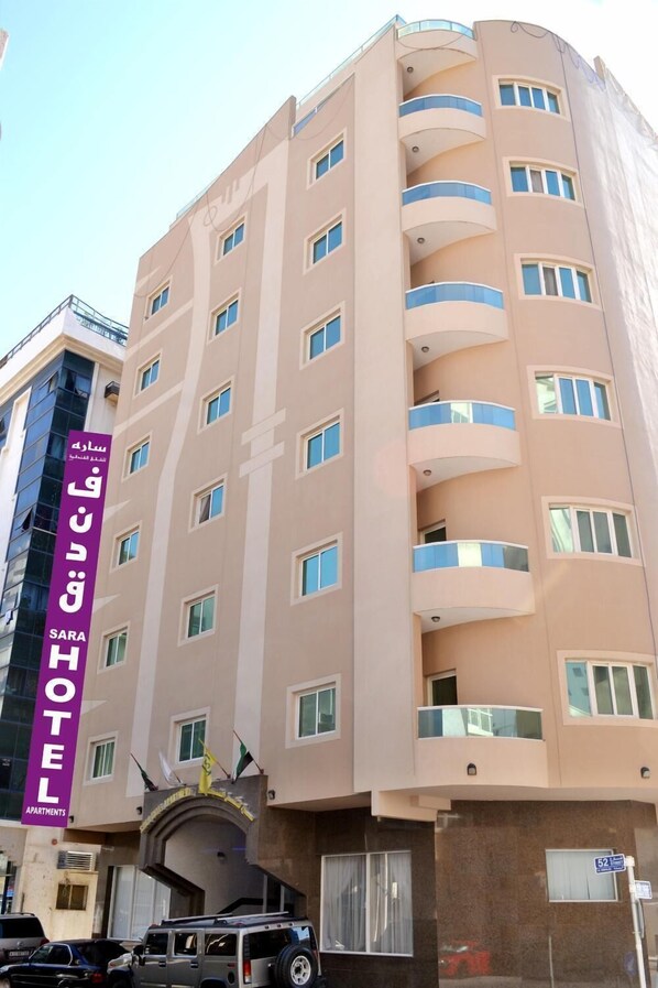 A multi-story hotel with a prominent purple sign indicating "SARA HOTEL" and "Apartments". - Sara Hotel Apartment (Ajman)