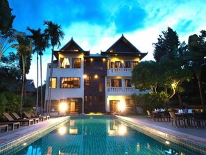 A hotel with a large pool, multiple balconies, and a tropical garden setting. - Baan Vartika at Ping (Chiang Mai)