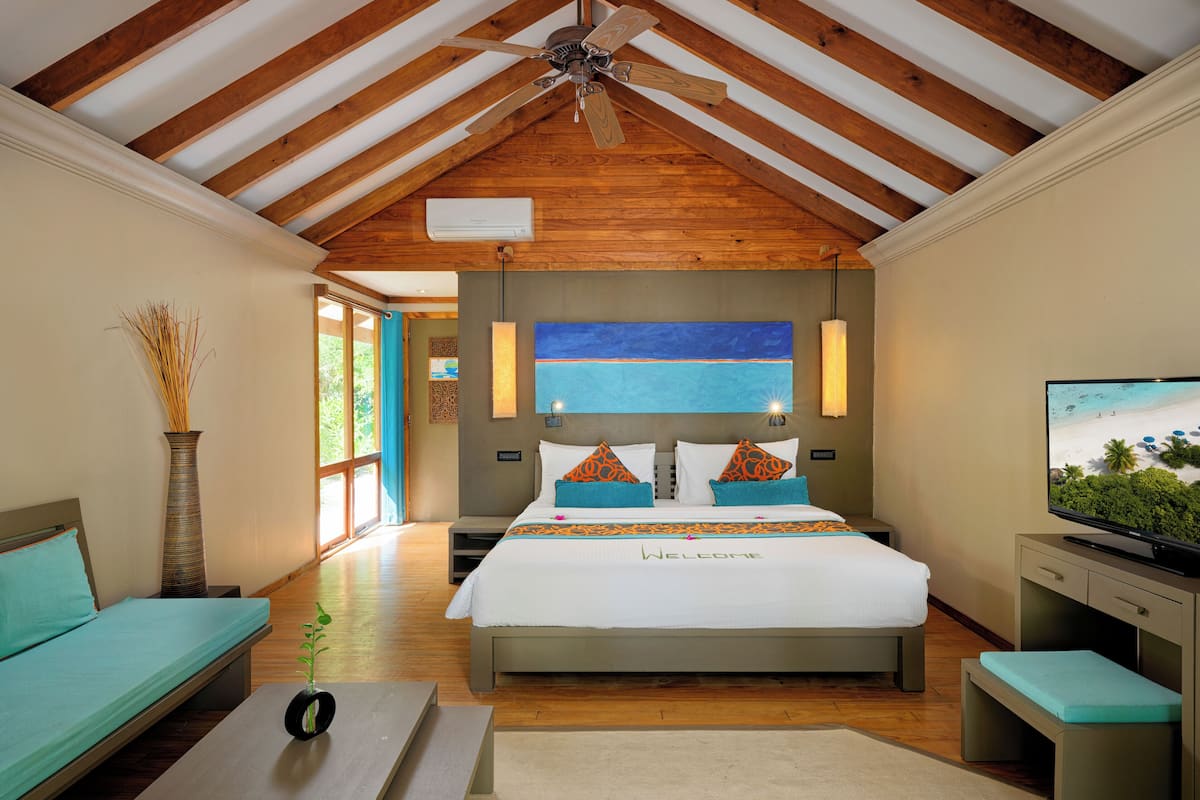 A spacious bedroom with a large bed, a television, and a ceiling fan.