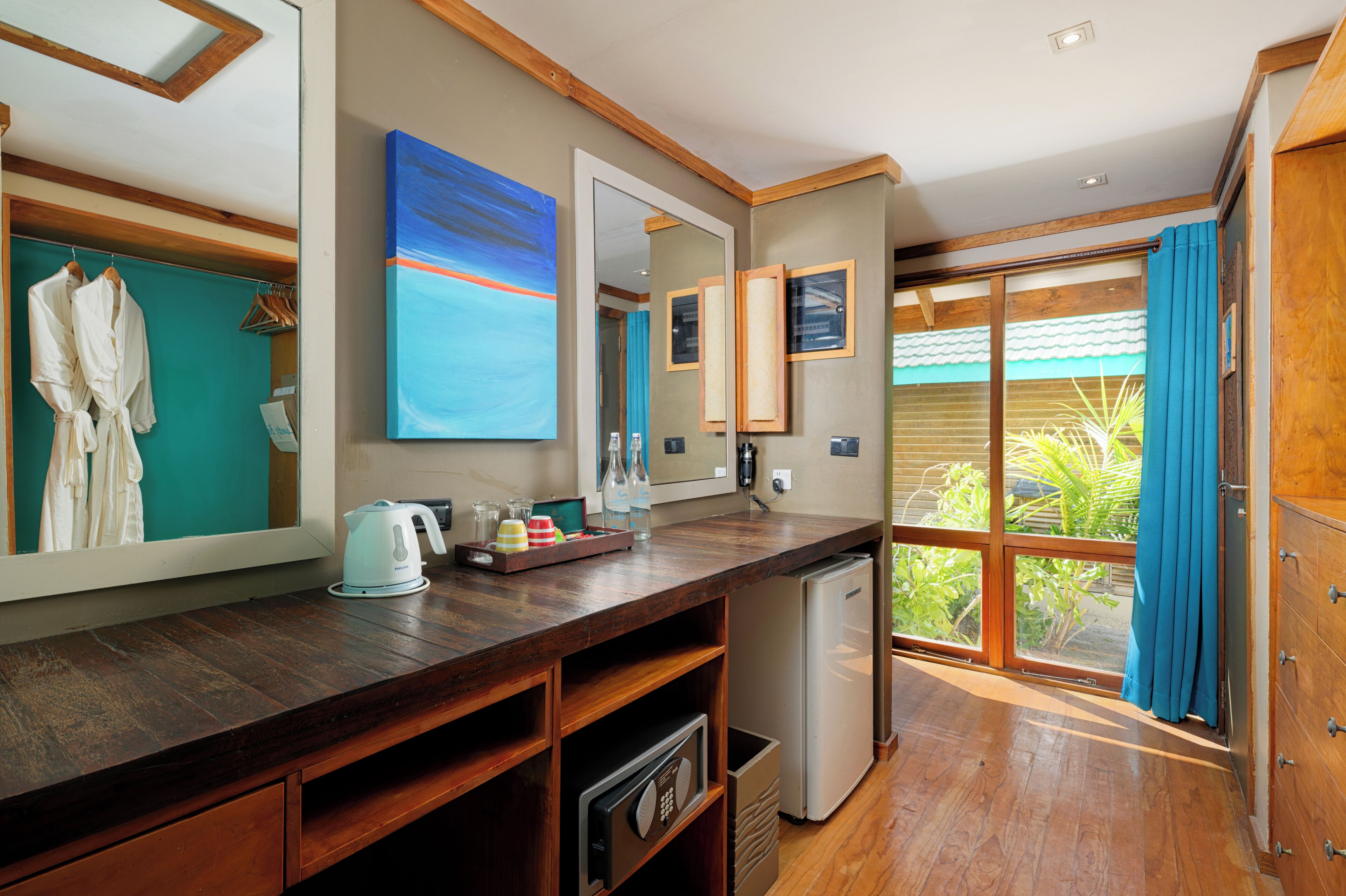 A modern bathroom with a wooden countertop, a small refrigerator, a mirror, and a view of the outdoors.