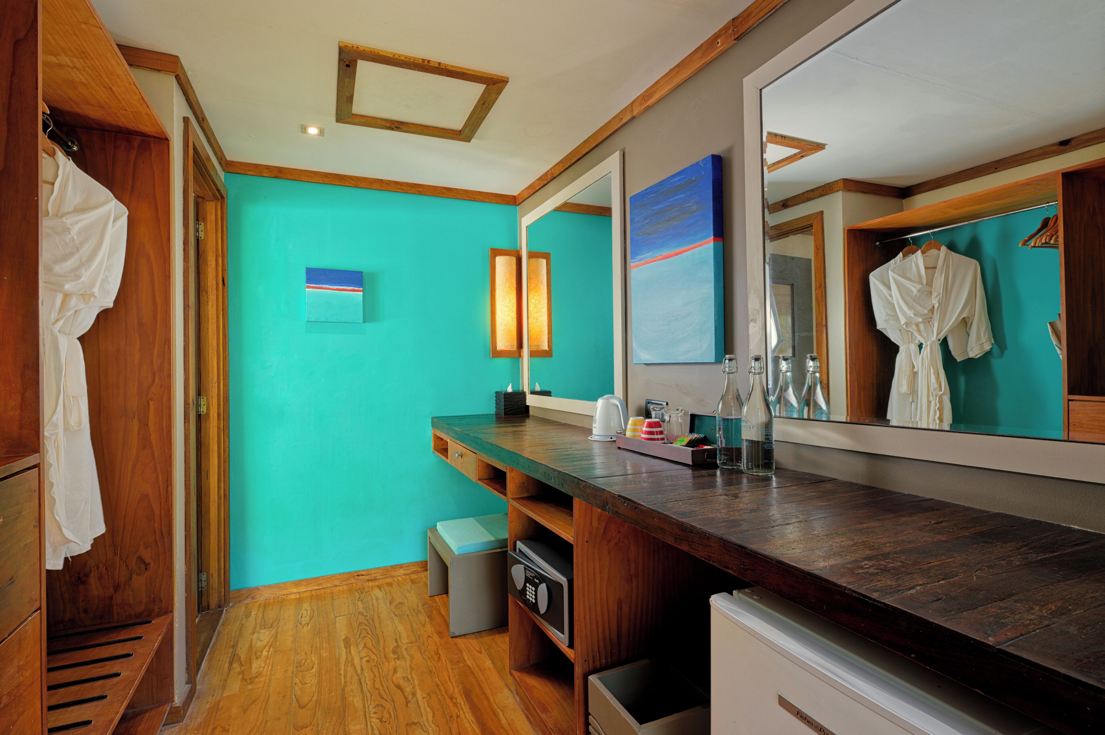 A modern bathroom with a wooden vanity, a large mirror, and a teal wall.