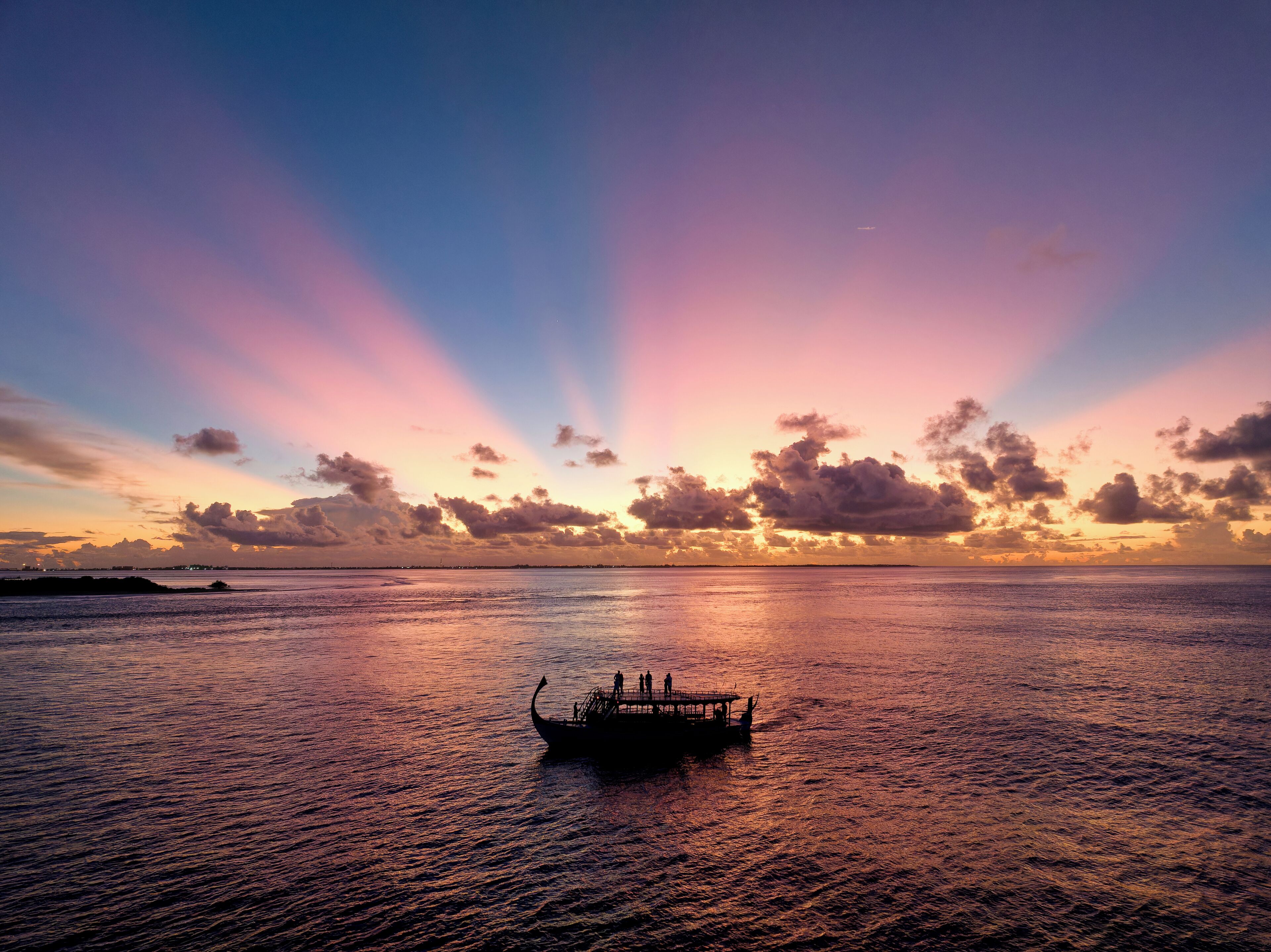 Un barco sobre aguas tranquilas con un atardecer al fondo.