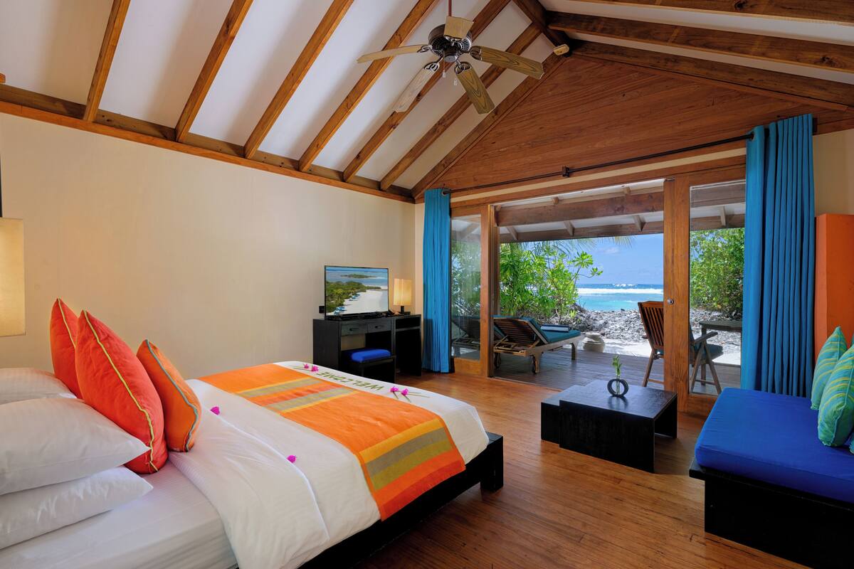 A bedroom with a bed, a desk, and a view of the beach.