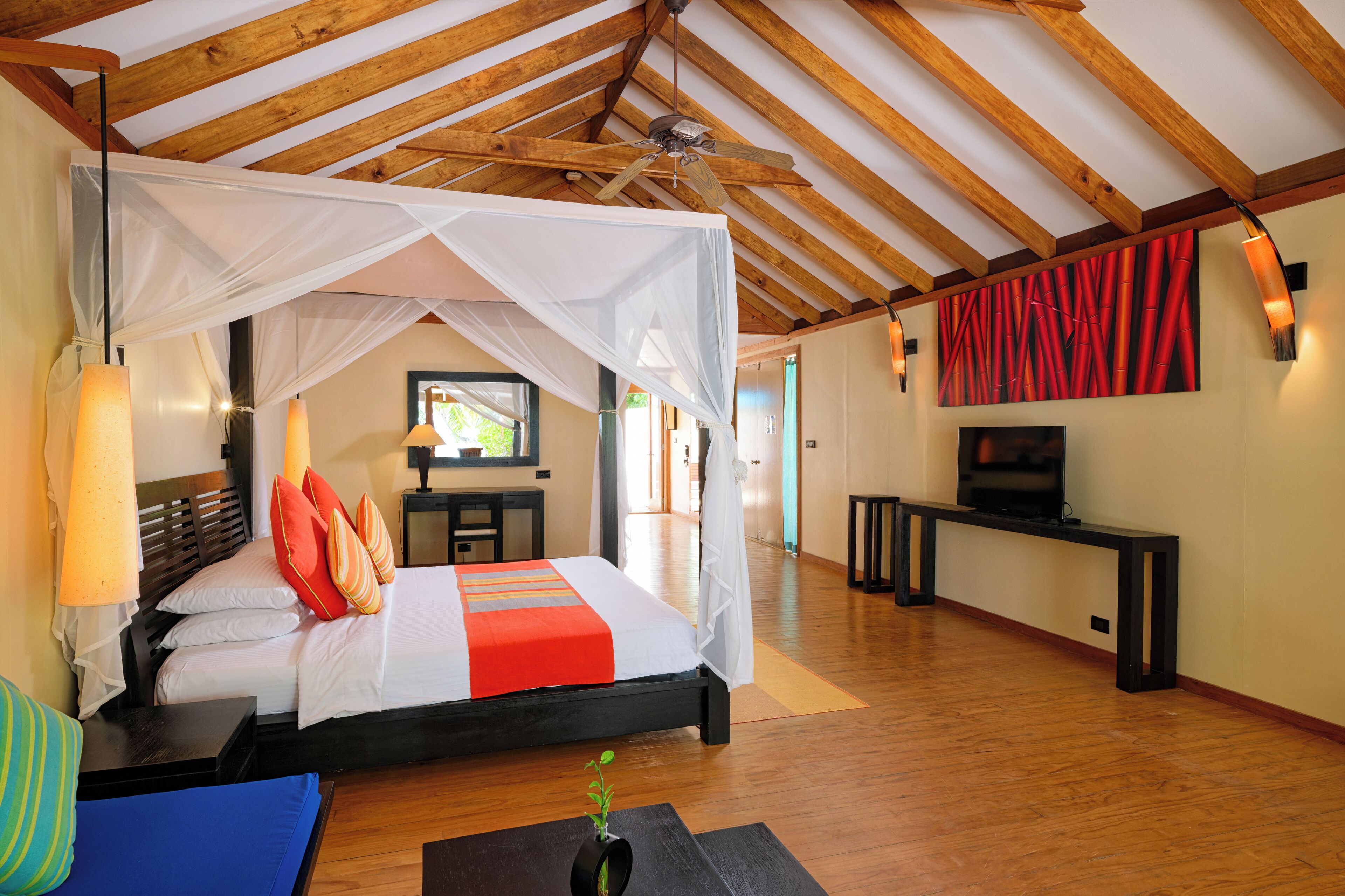 Un dormitorio con cama a dosel, mesitas de noche, televisor y vistas al exterior.