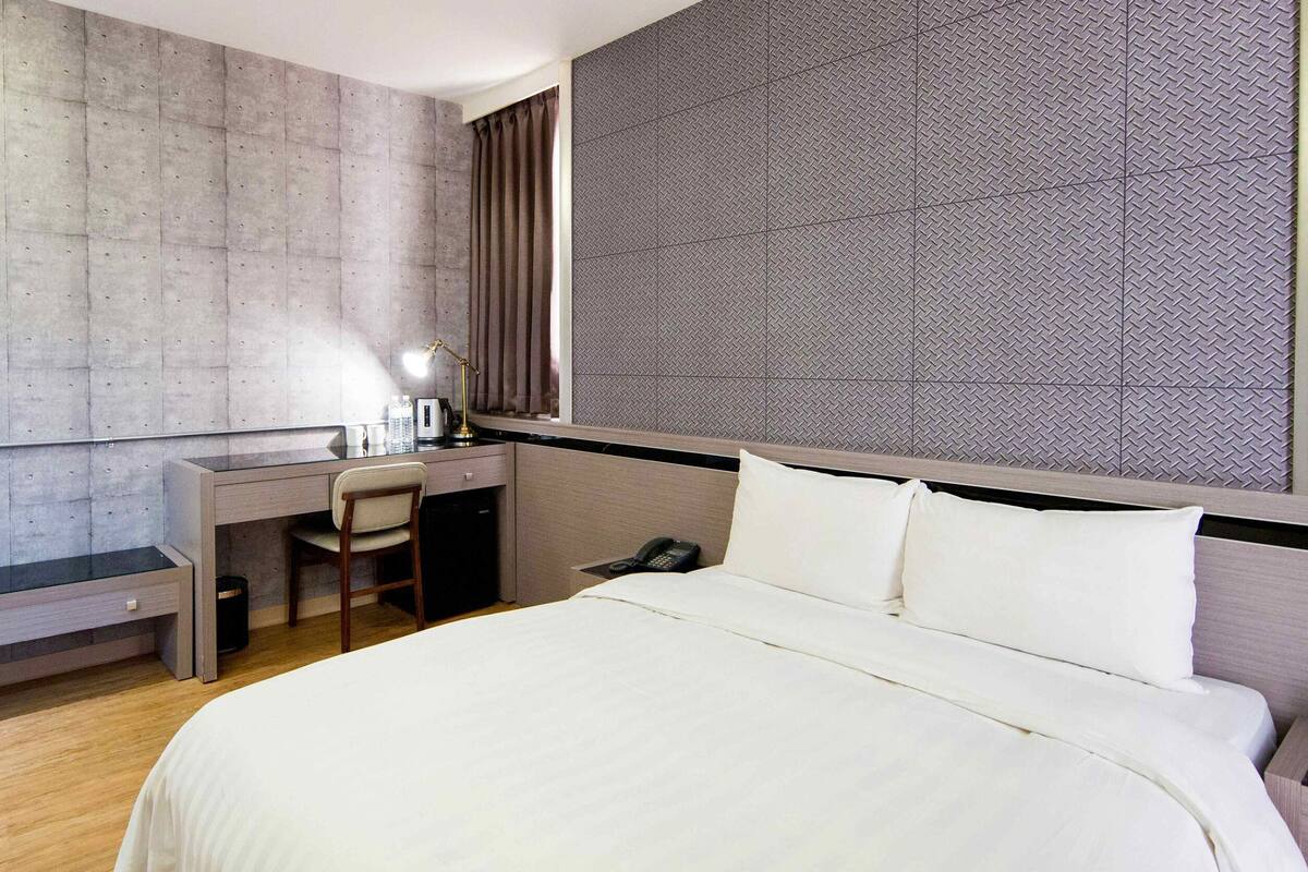 Een hotelkamer met een bed, bureau, stoel, televisie en telefoon.