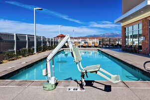 Una piscina con un tobogán, un puesto de socorrista y una vista despejada de montañas al fondo.