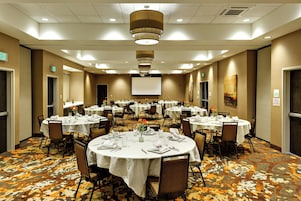 A conference room with multiple tables set for dining, equipped with chairs, tables, and a projector screen.