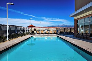 A swimming pool with lounge chairs and a view of mountains.