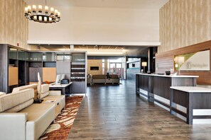 A hotel lobby with a reception desk, seating area, and a fireplace.