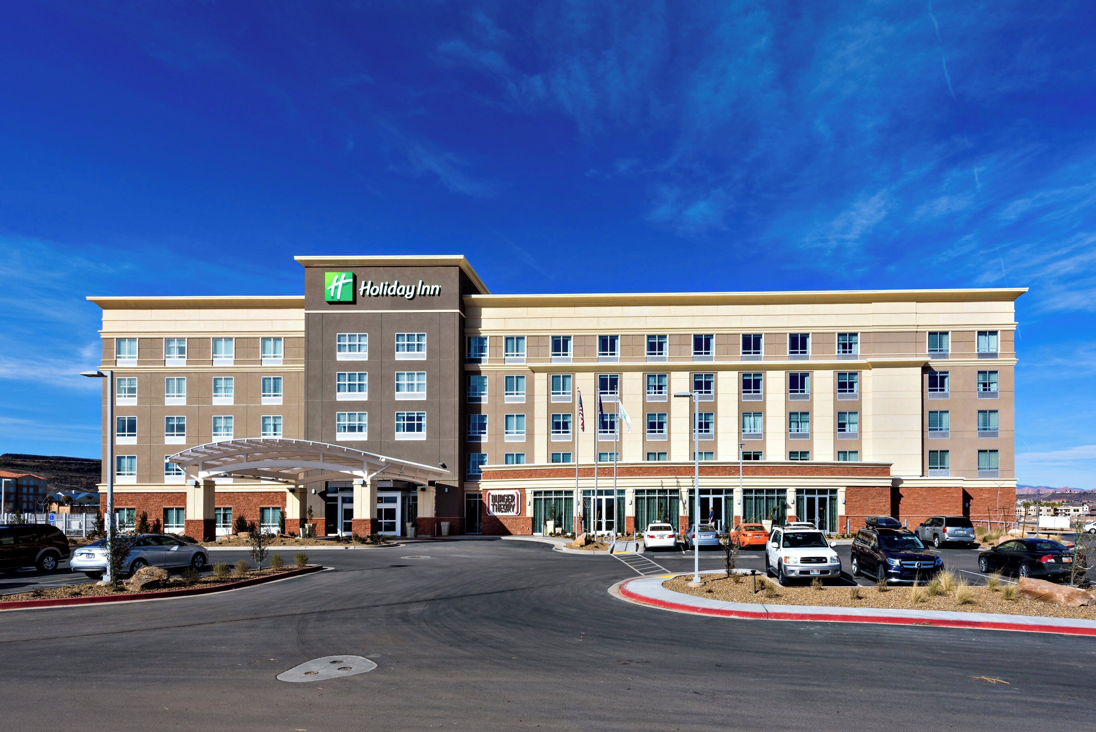 Un hotel Holiday Inn con entrada central, varios pisos y un estacionamiento.