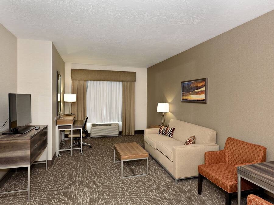 A hotel room with a desk, a sofa, a coffee table, and a TV.