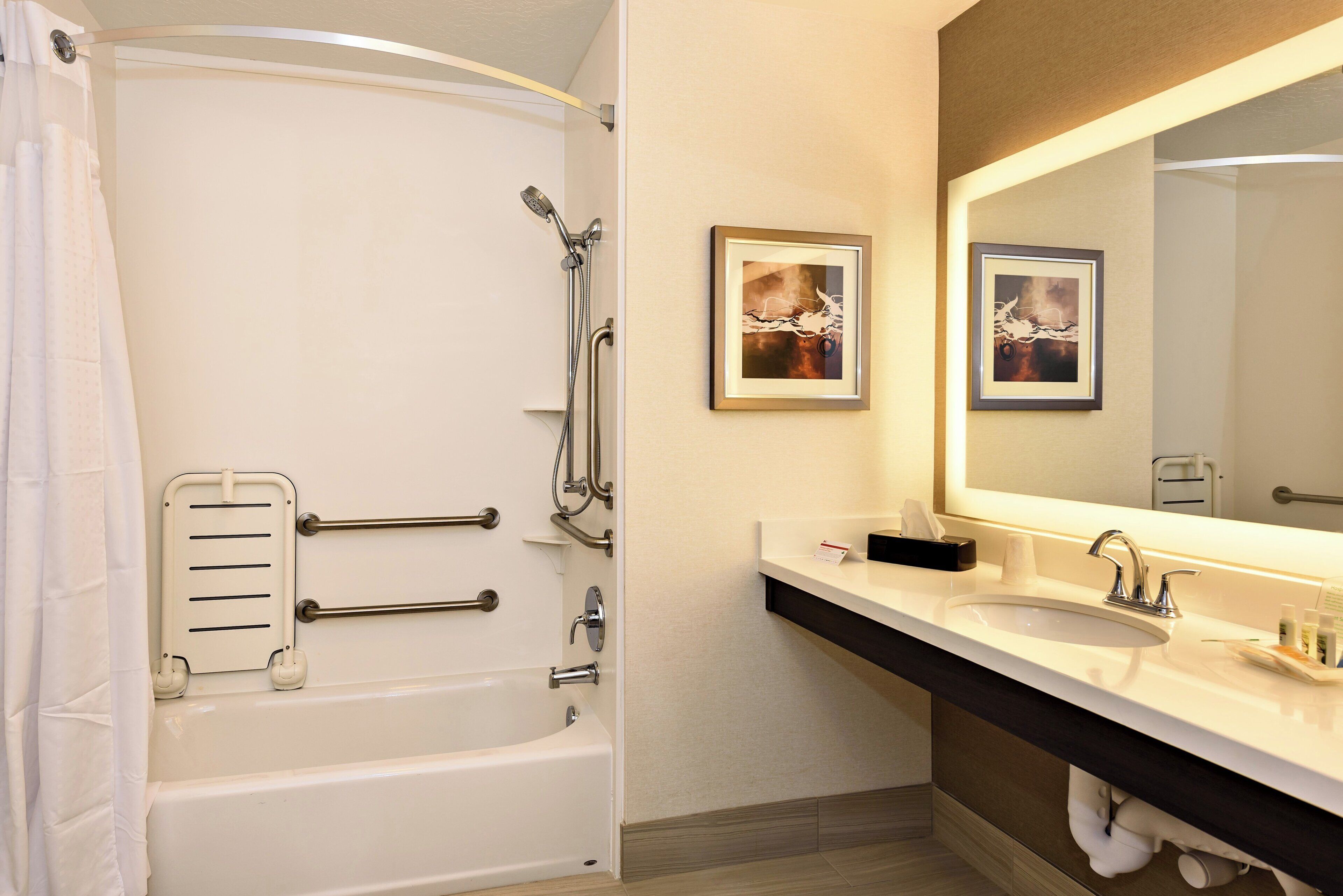 A bathroom with a bathtub, a sink, a towel rack, and two framed pictures on the wall.