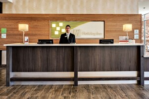 Un mostrador de recepción de hotel con un fondo de paneles de madera, una placa y un letrero que dice "Holiday Inn".
