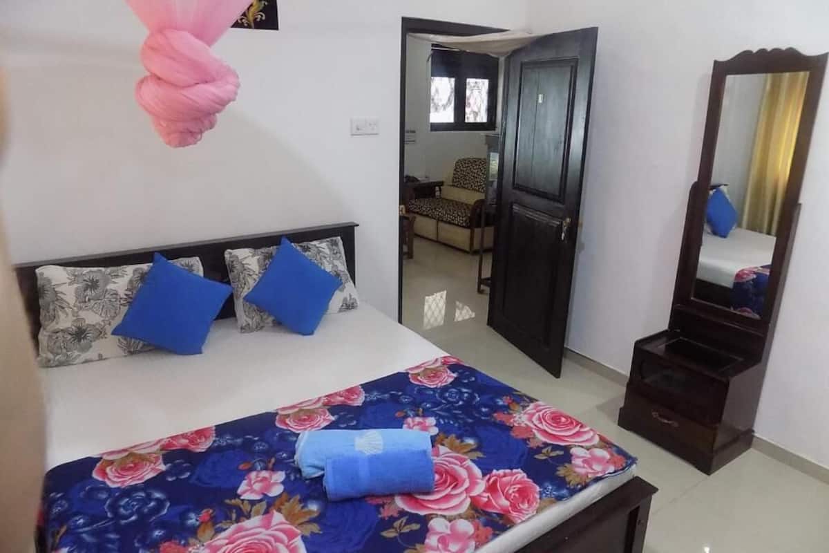 A bedroom with a bed, a mirror, and a door leading to another room.