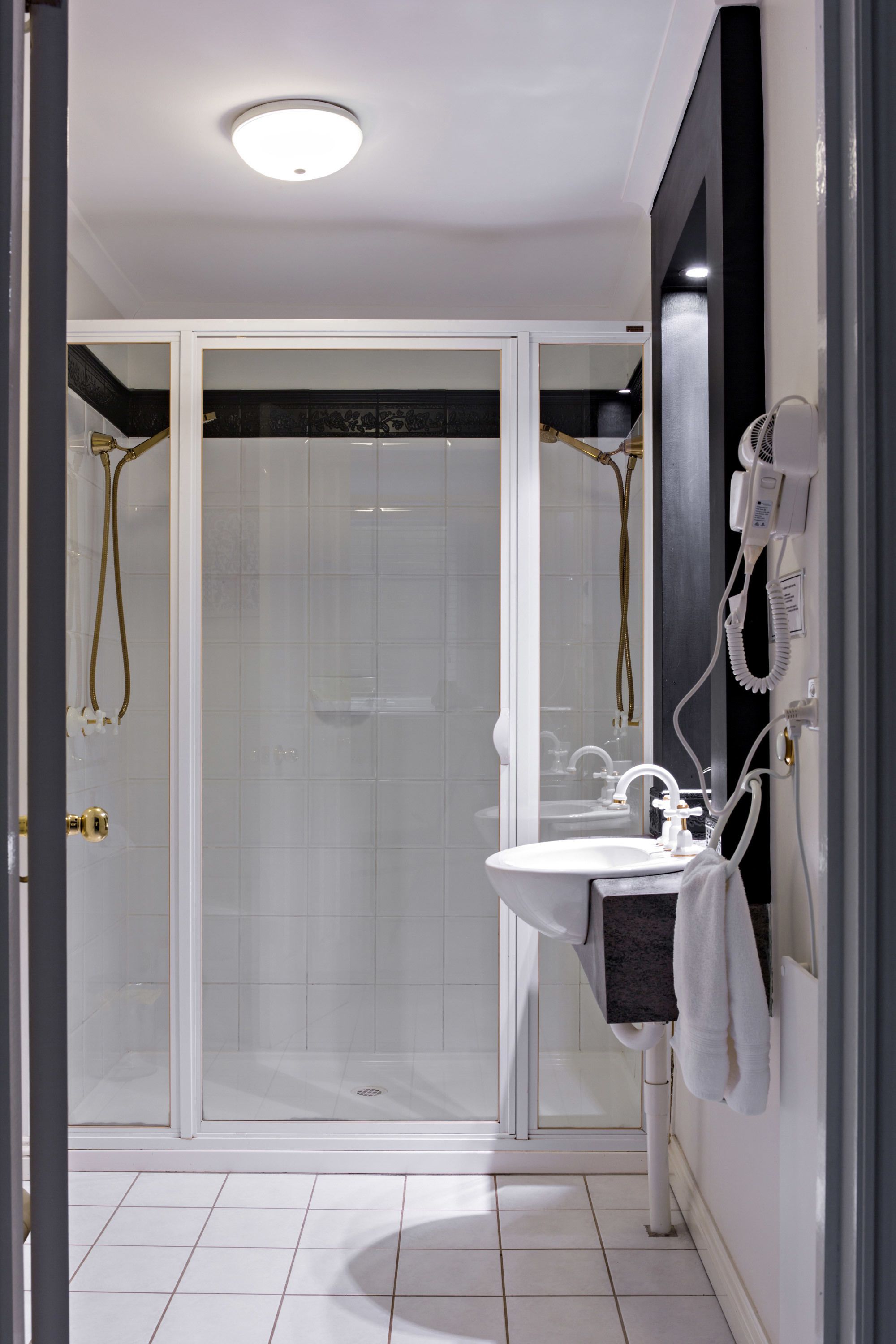 Une salle de bain moderne avec une douche à parois de verre, un lavabo blanc et un porte-serviettes.