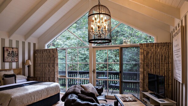 A bedroom with a large bed, a leather sofa, a TV, and a chandelier. - Belle Le Vie (Sassafras)