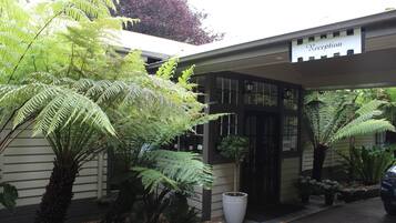 A reception area with a sign, a potted plant, and a car parked outside.