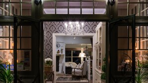 A warmly lit entrance with a chandelier, a patterned wall, and a cozy seating area with a rug. - Belle Le Vie (Sassafras)
