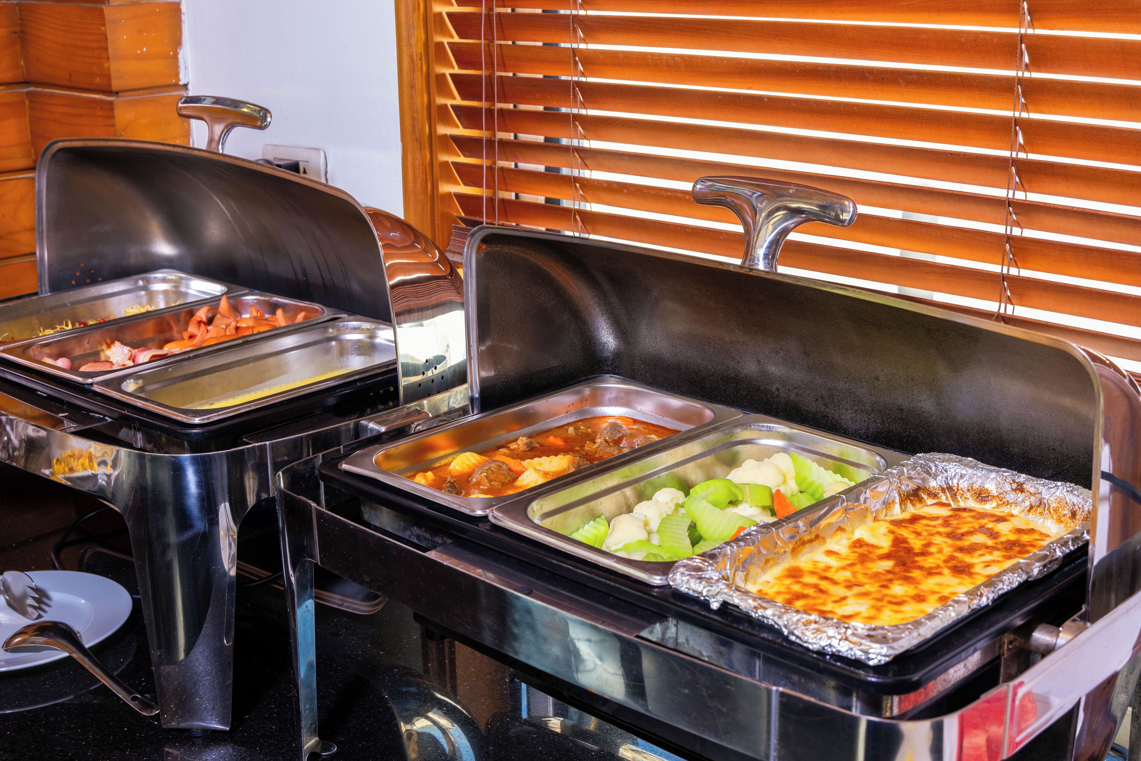 A buffet setup with multiple serving trays containing various dishes.