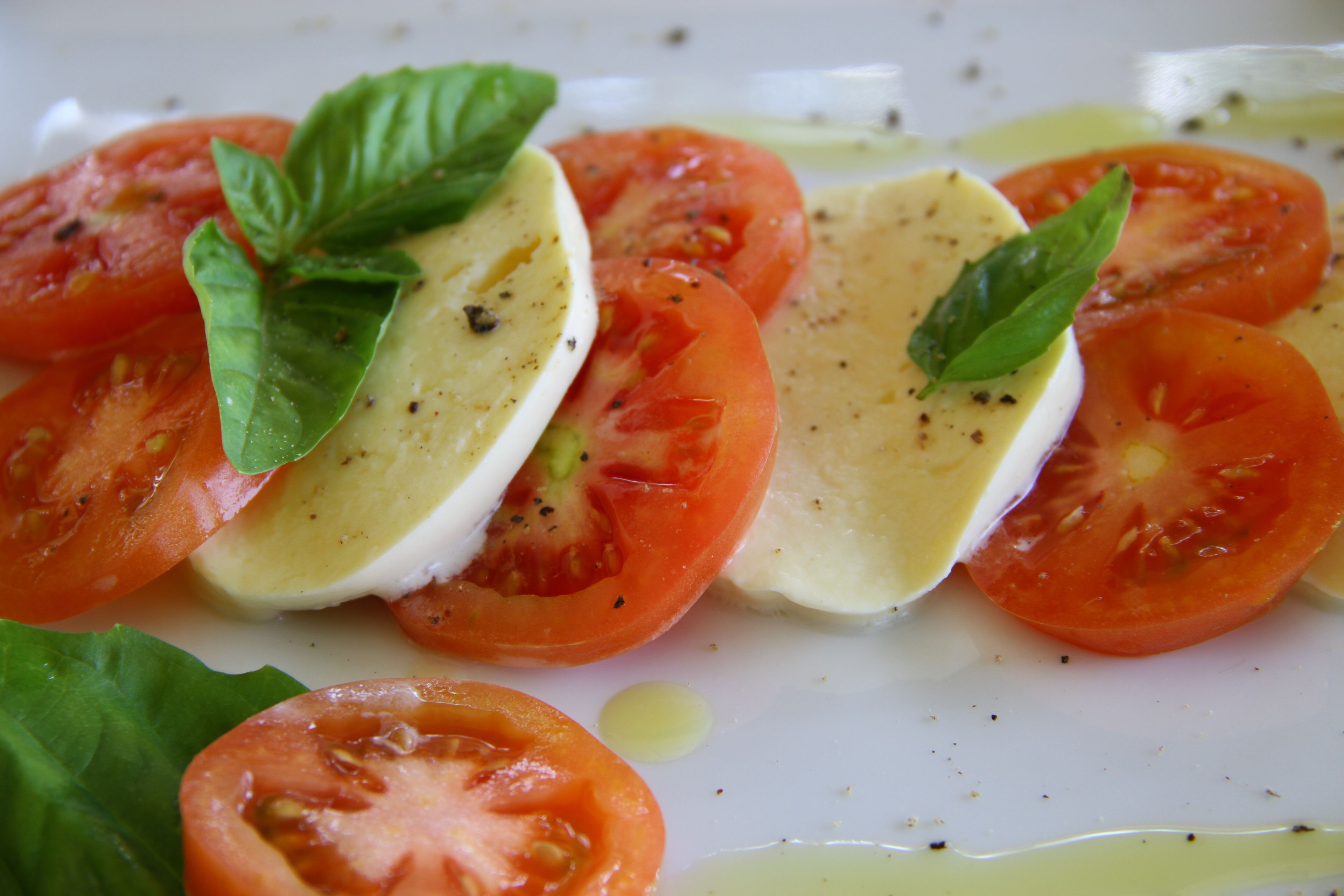 A plate with sliced tomatoes and mozzarella cheese, garnished with basil leaves.