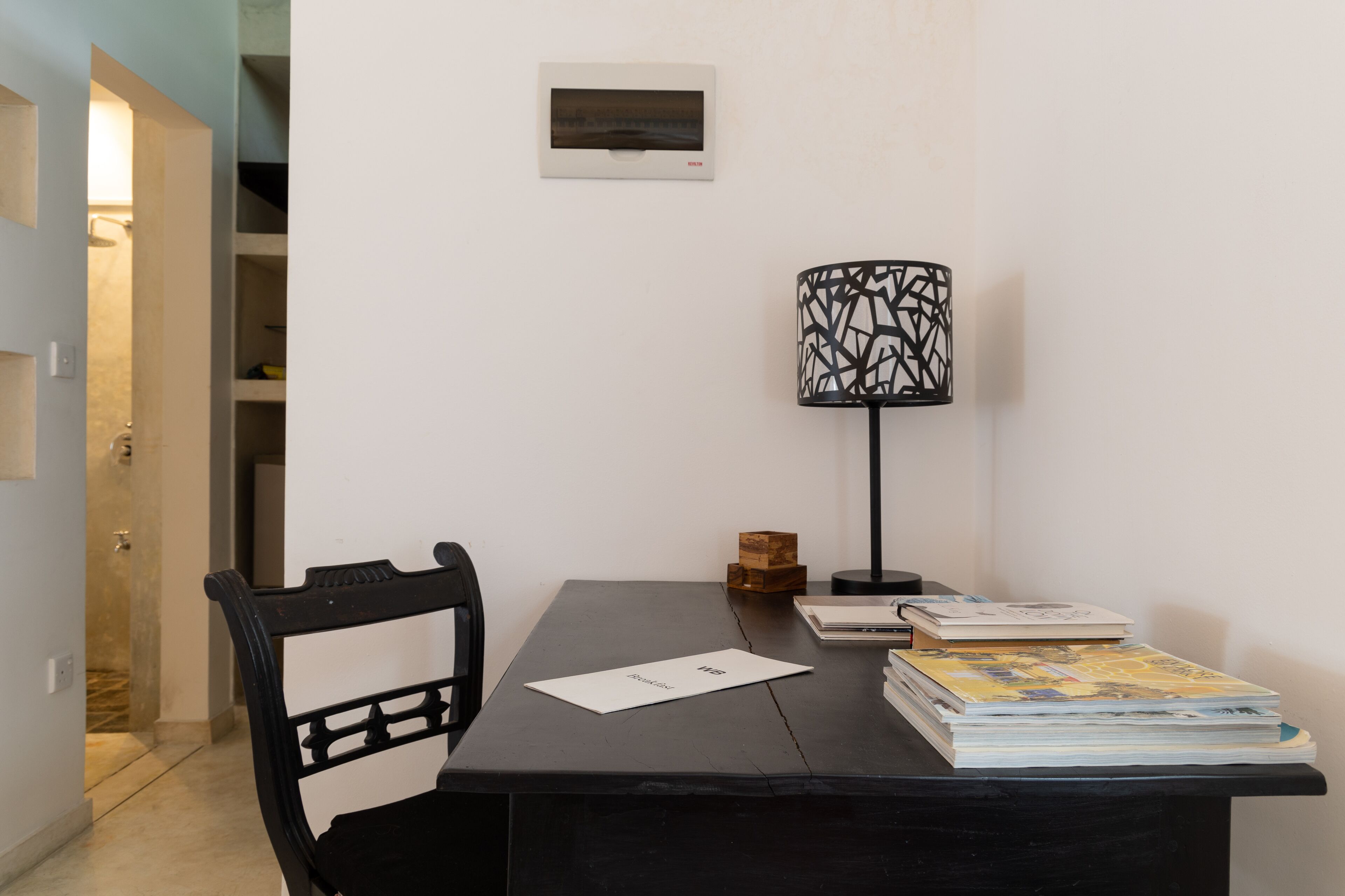 Ein Zimmer mit Schreibtisch, Stuhl, Lampe und Büchern.