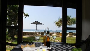 A table with a view of the beach, a bottle of wine, glasses, bread, and a plate with a leaf. - WB Villa (Unawatuna)