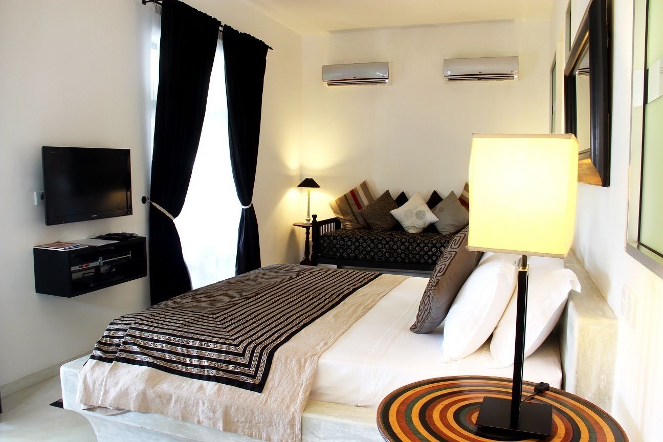 A hotel room with a bed, a TV, a lamp, and a bedside table.