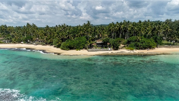 A tropical beach resort with clear turquoise waters, a sandy beach, and dense palm trees. - WB Villa (Unawatuna)