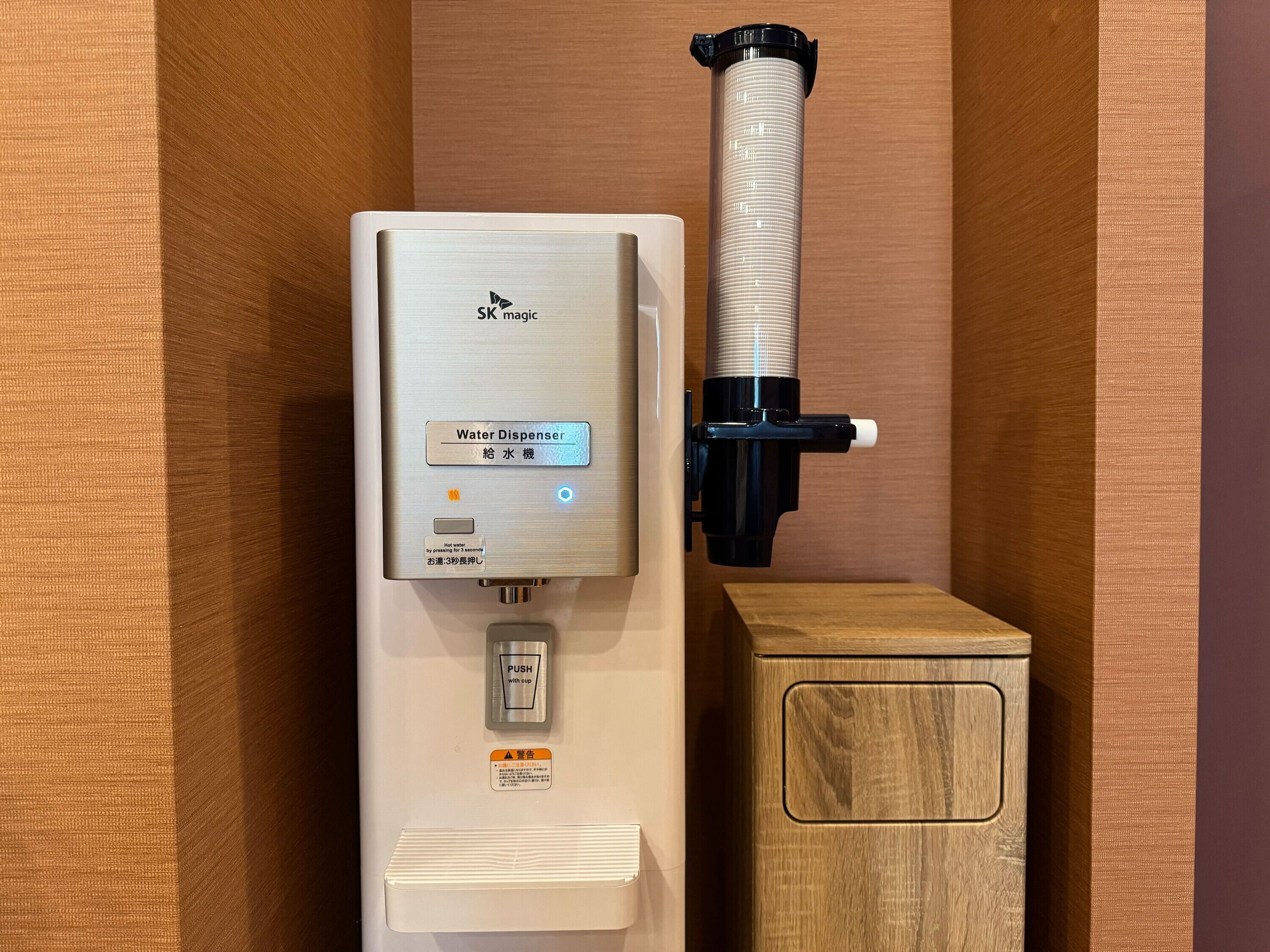 Dispensador de agua con panel de control, un botón pulsador y una botella de agua unida.