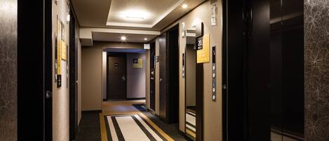A hotel corridor with a striped carpet, elevator doors, and a sign indicating the 20th floor.