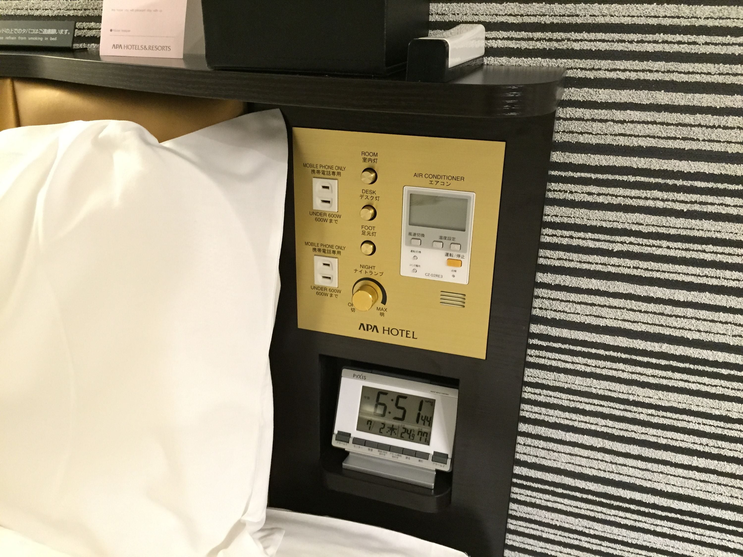 Panel de control de una habitación de hotel con un reloj digital que marca las 6:51.
