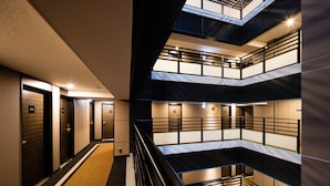 Un hôtel à plusieurs étages, avec un escalier central, de nombreuses chambres à chaque étage et un design moderne.