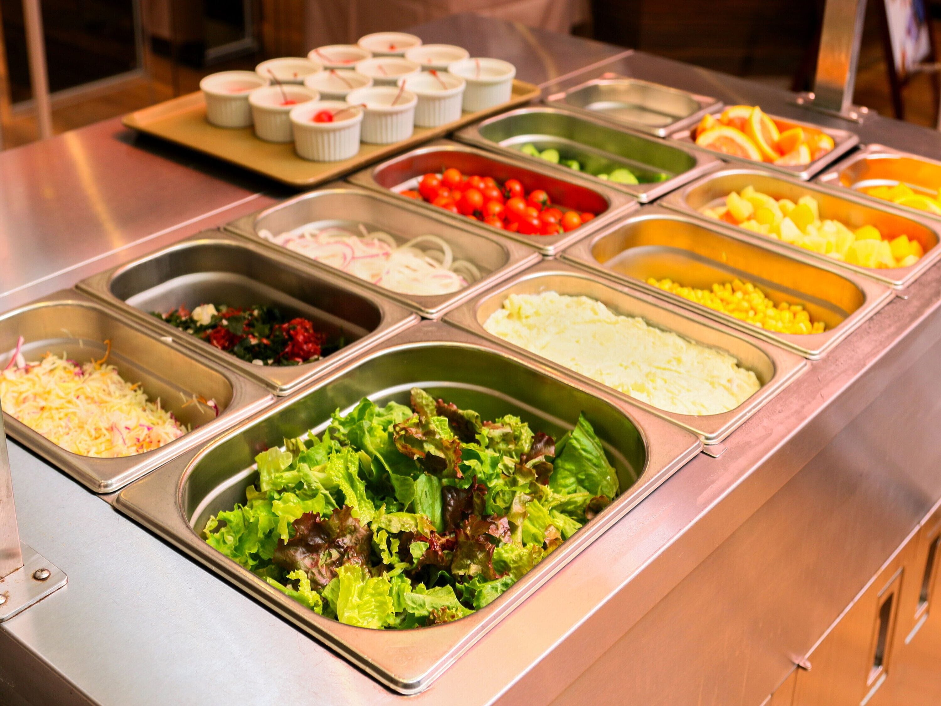 A buffet with various food options including salads, fruits, and other dishes.