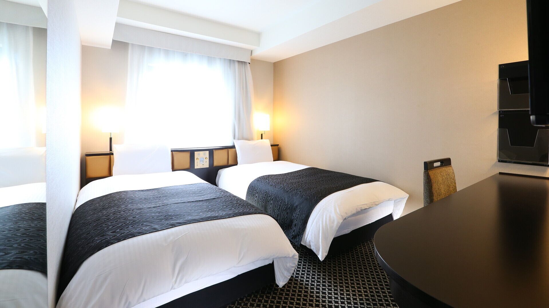 Een hotelkamer met twee bedden, een bureau, een stoel en een televisie.