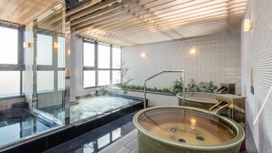 Un spa moderne doté d’un jacuzzi à ciel ouvert, d’un espace de relaxation séparé avec eau chaude et d’un plafond en bois.