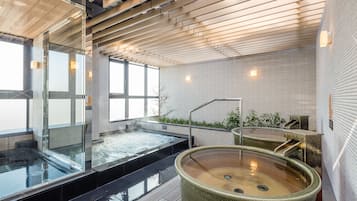 Relax in a serene spa area with a large hot tub and a smaller hot tub, surrounded by lush greenery and natural light.