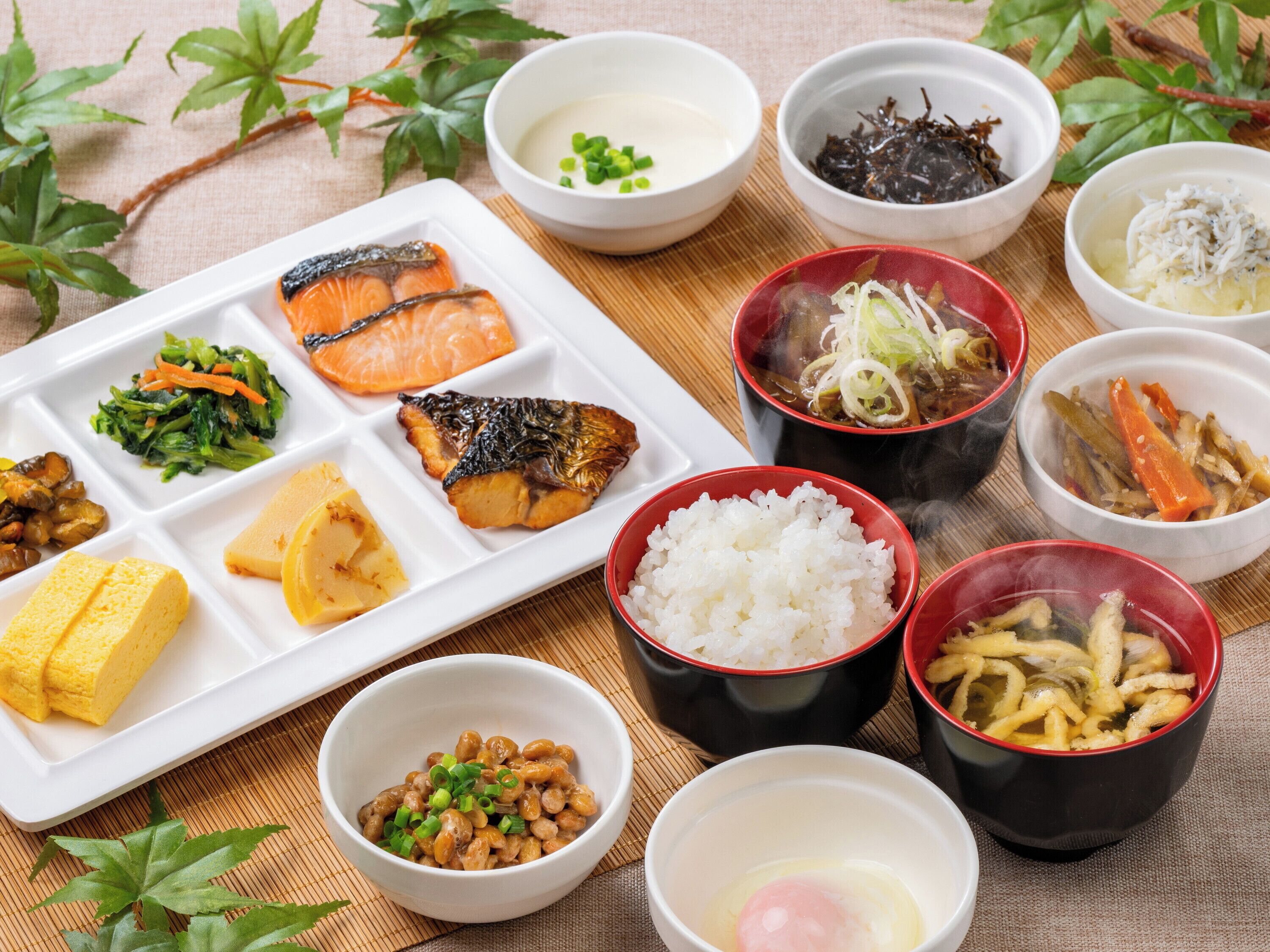 A variety of Japanese dishes including sushi, rice, and soup, arranged on a table with a placemat.
