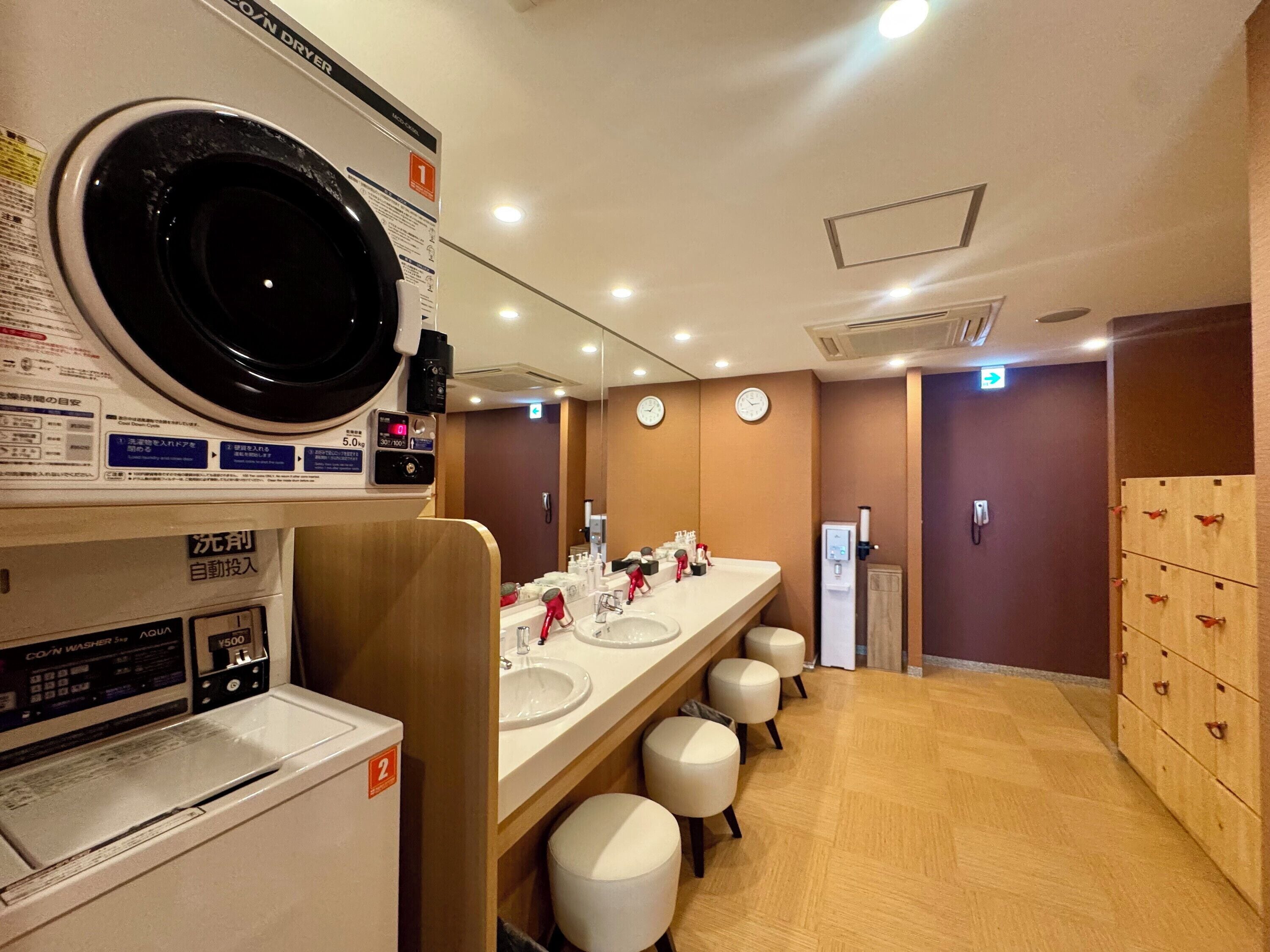 A hotel bathroom with a washing machine, a sink, and a mirror.