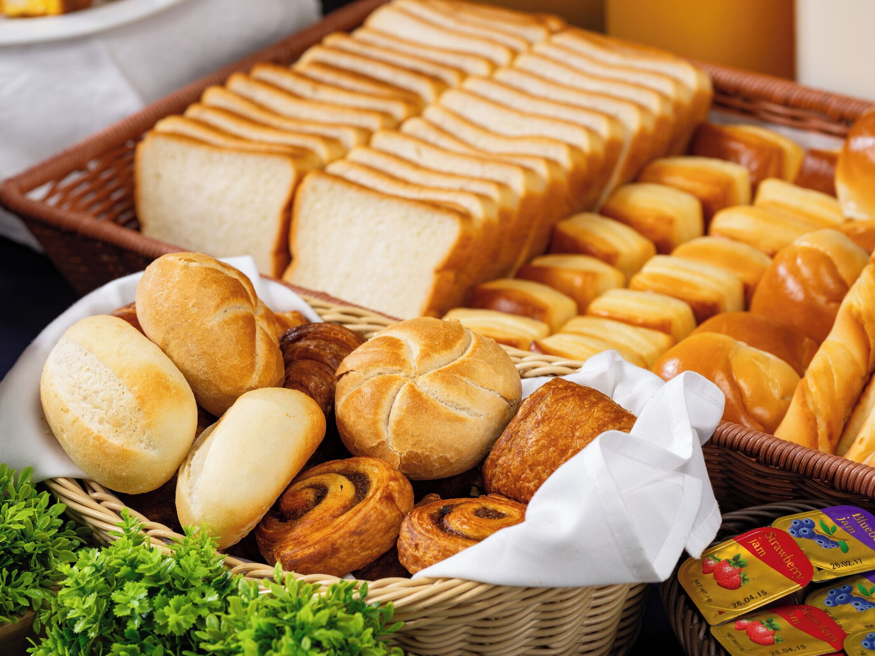 A variety of breads and pastries in a wicker basket.