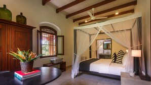 Un dormitorio con cama a dosel, un armario de madera, una mesa con una planta y un ventanal con vistas.