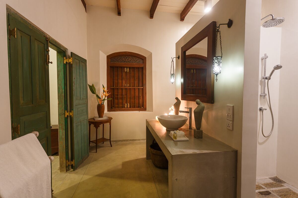 A bathroom with a large mirror, a sink, and a shower.