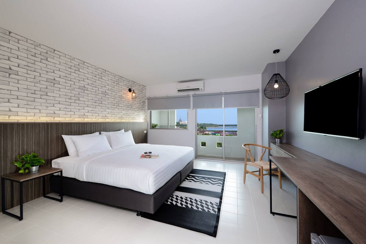 Un dormitorio moderno con una cama grande, un escritorio, una silla y un televisor.